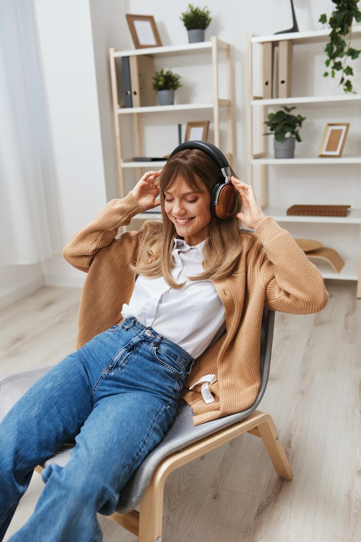 cheerful-young-blonde-lady-warm-sweater-headphones-listen-enjoy-fav-songs-dancing-sitting-armchair-modern-home-interior-music-time-relaxing-cool-playlist-concept-copy-space_163305-262782